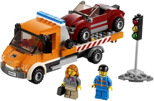 Brick-built flatbed tow truck winching a small car onto its tilted bed