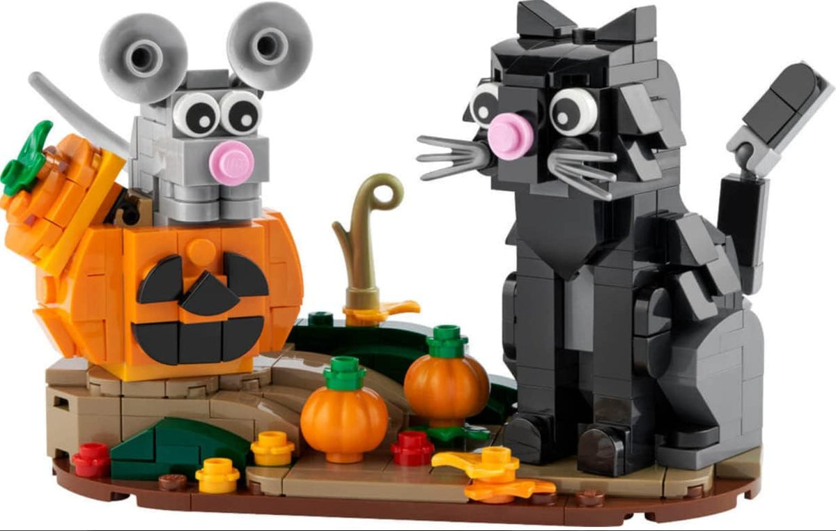 Brick Halloween scene with a cat, a mouse hiding in a large orange pumpkin and fall flowers on a round base