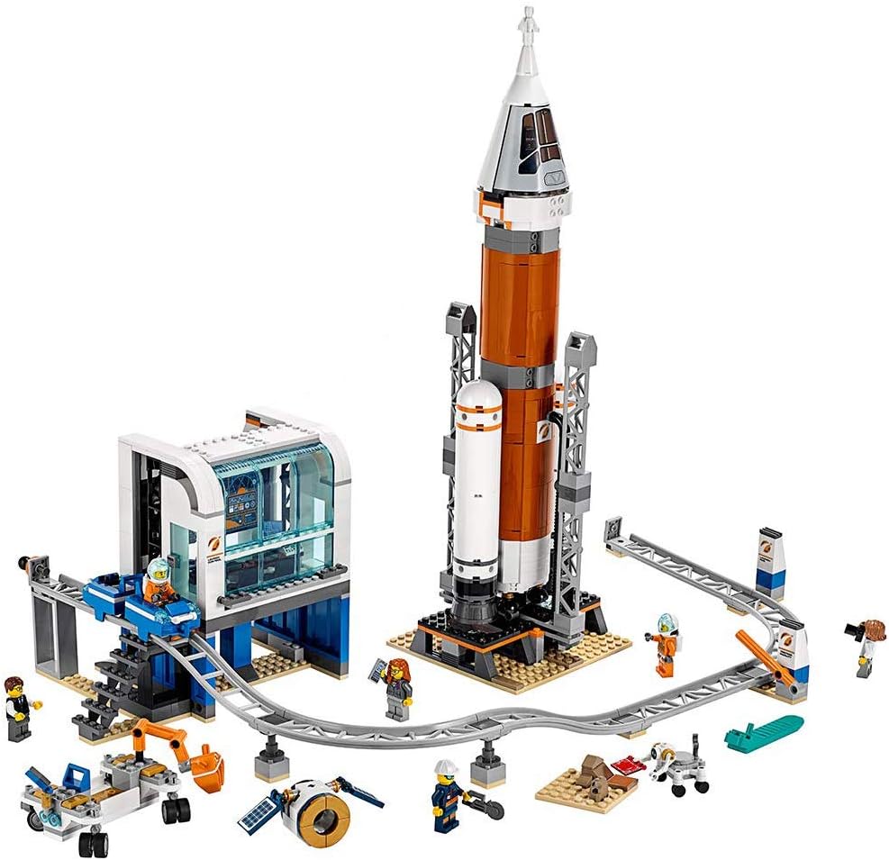 Tall brick rocket in a launch tower beside a control center and monorail