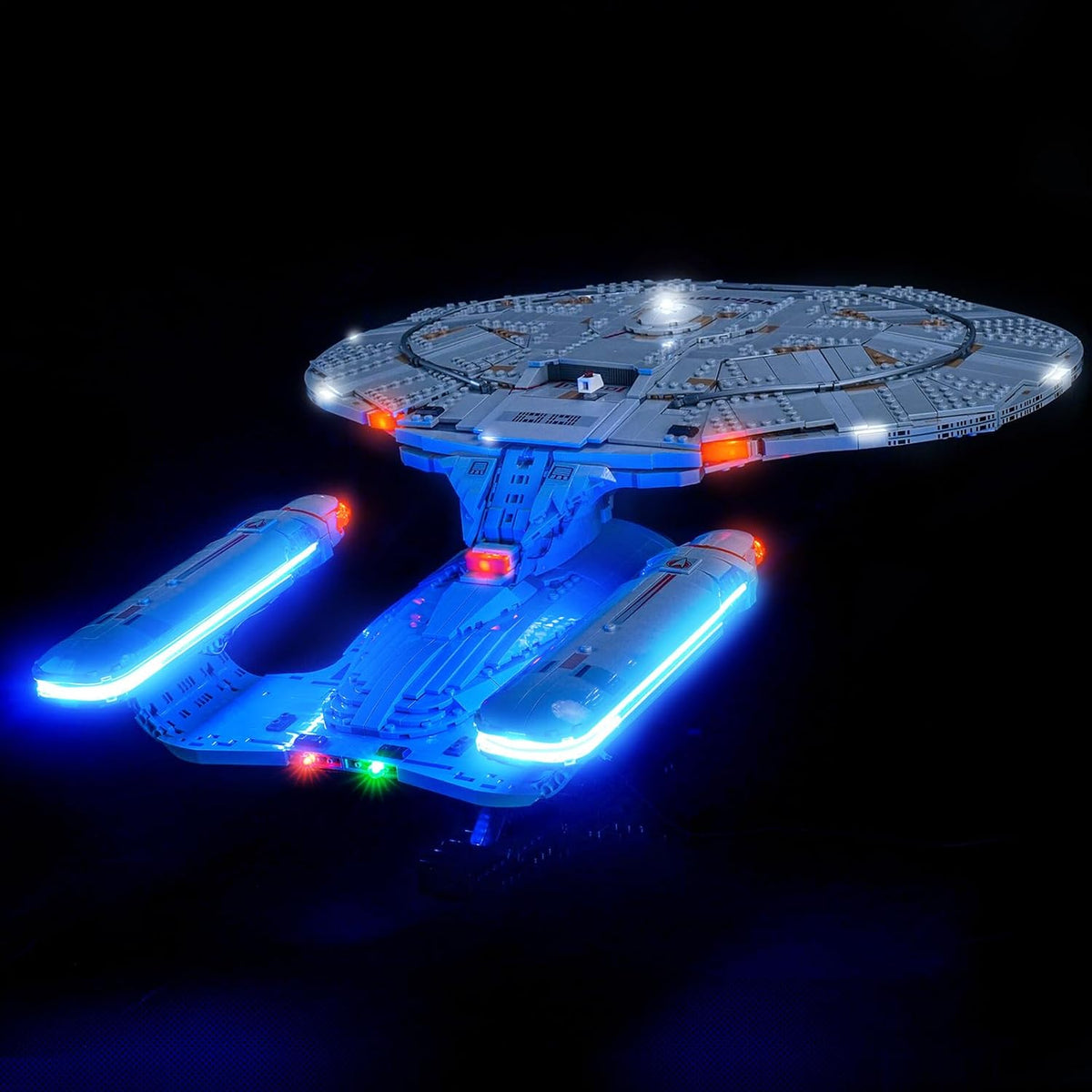 Sci-fi starship brick model with glowing blue and red LED lights on its saucer and engines – view 2