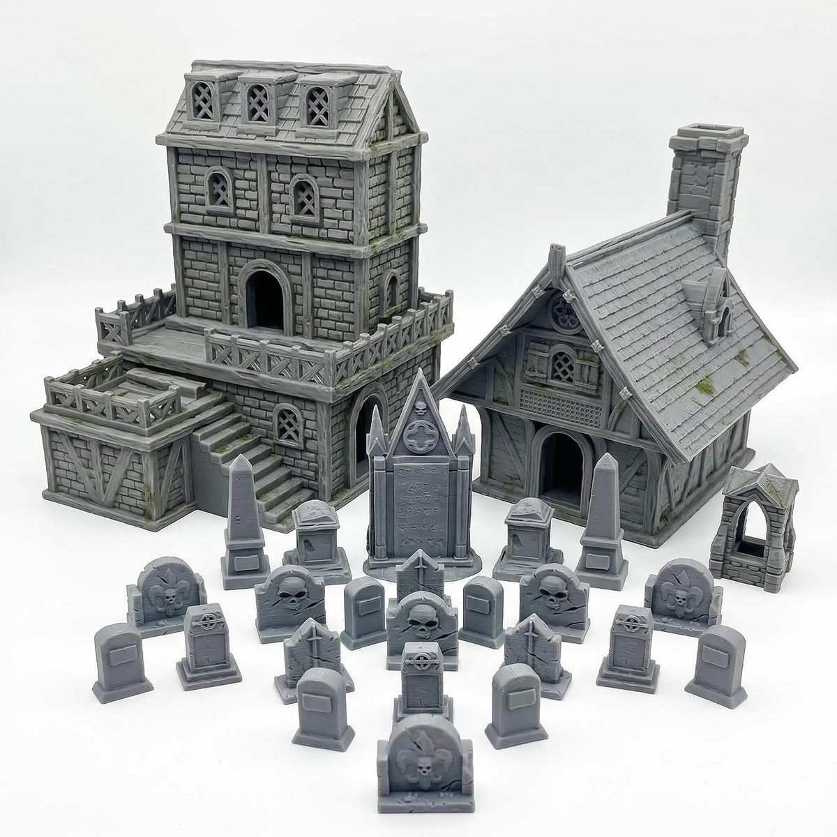 Unpainted gray medieval stone house and graveyard terrain pieces on a tabletop