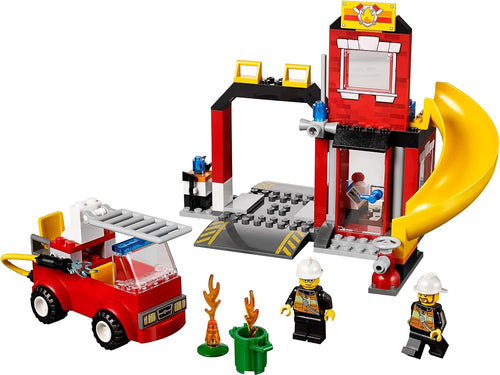 Small brick fire station with ramp and chute next to a red fire truck and two firefighters