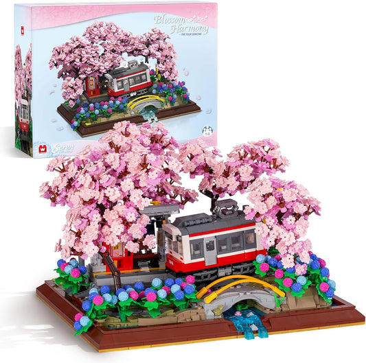 Brick-built diorama of a small train passing pink cherry blossom bonsai trees