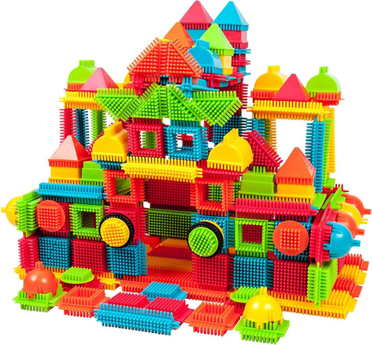 Magnetic tile marble run tower with funnels next to colorful bristle blocks