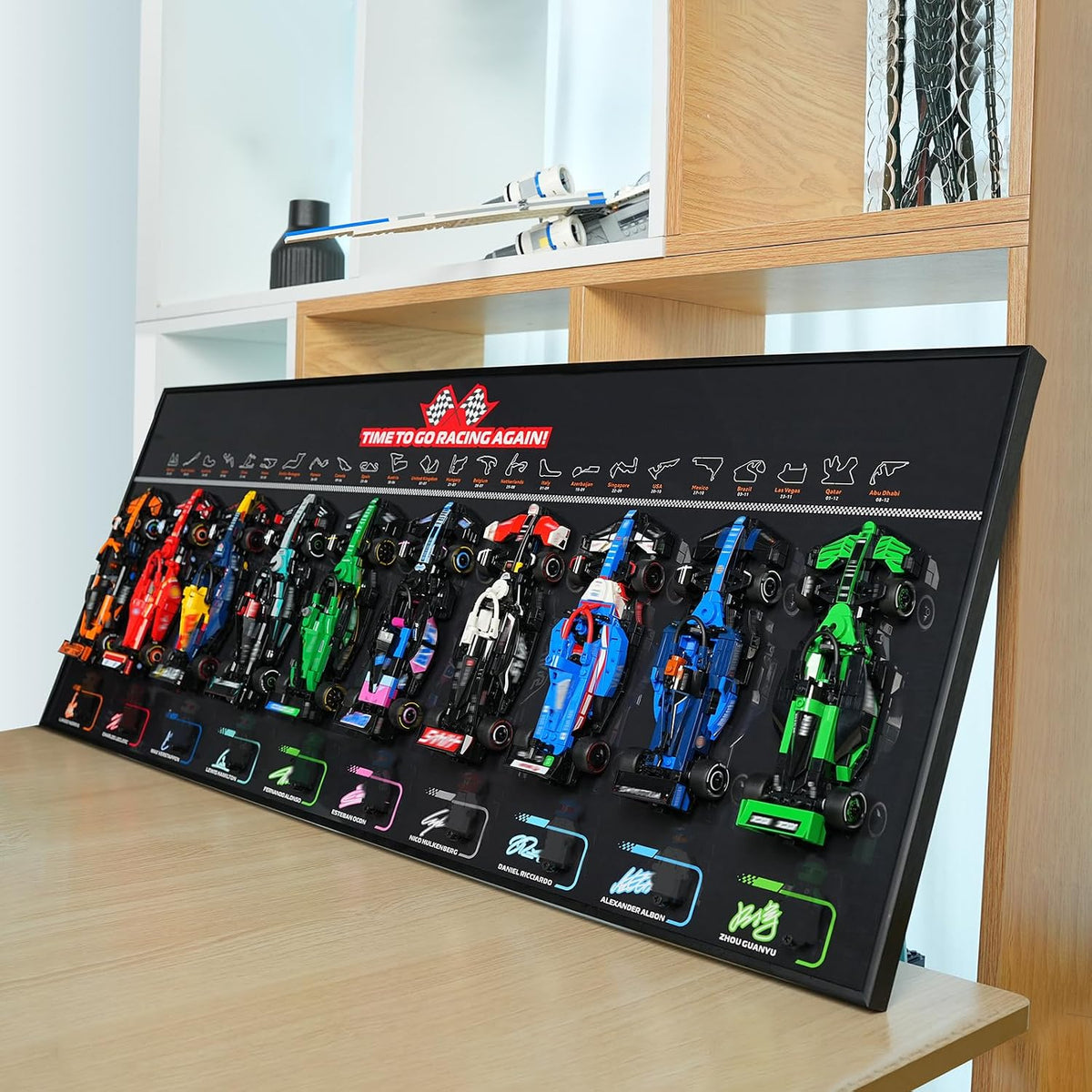 Black wall board displaying ten small brick race cars in two rows