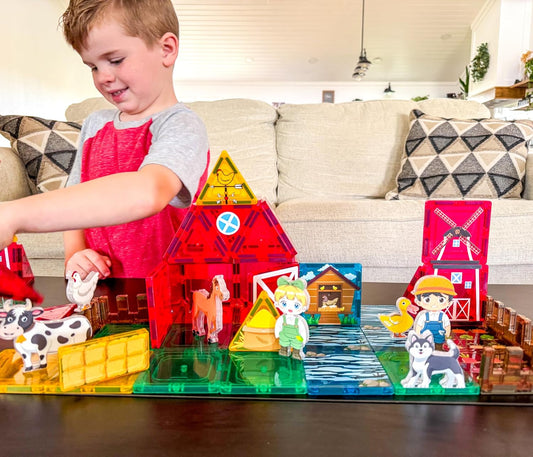 Magnetic tile roads with toy cars beside a tile barn and farm animal figures